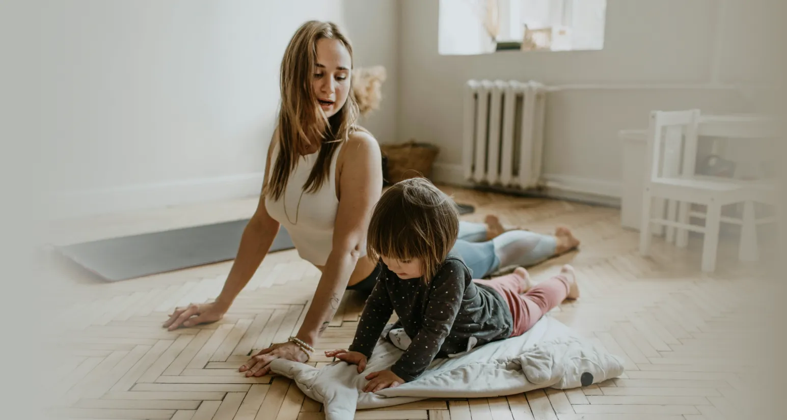 a young women doin yoga with her child inside a bright room